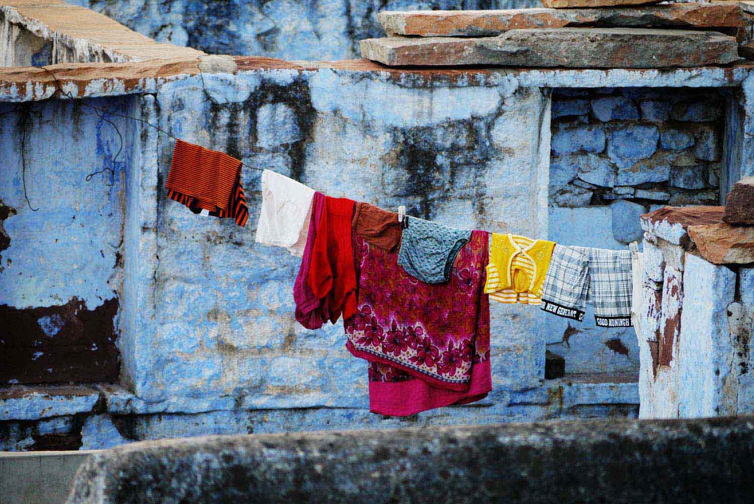 Bunte Kleidung an Wäscheleine vor hellblauer Wand