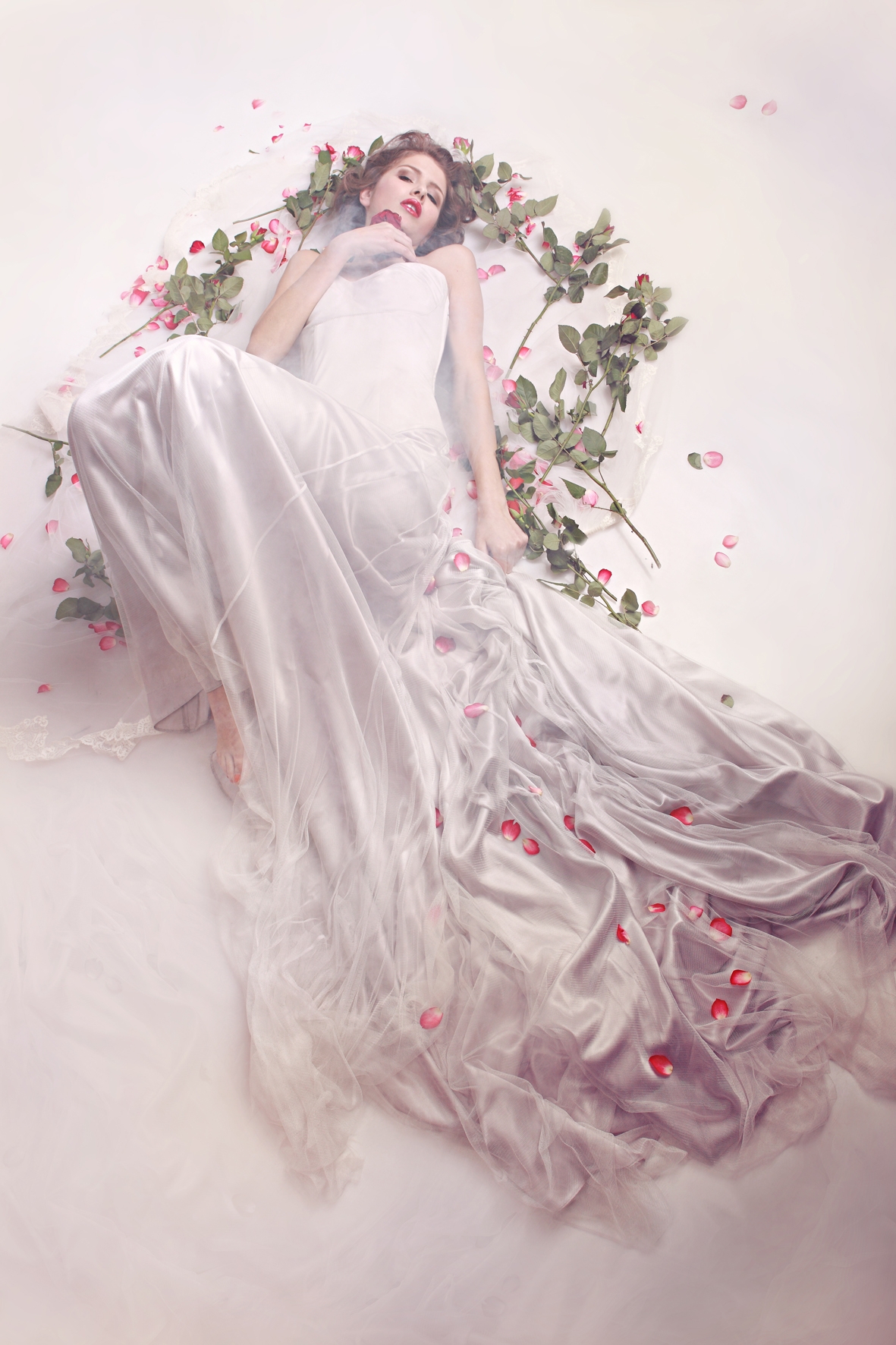 Model im Brautkleid von IOSOY Barbara Weigand, liegend, umgeben von Rosen 