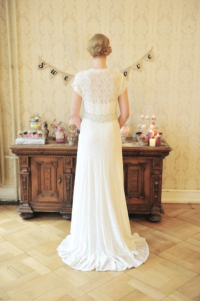 Rückansicht von Model im Brautkleid mit Spitze von perera/rüsche vor Möbeln und Tapete im Vintagestil