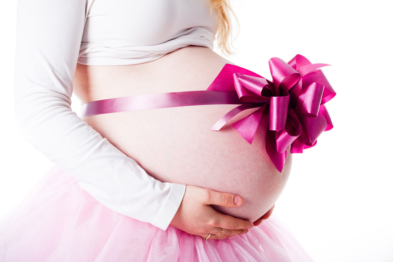 Mit einer Geschenkschleife dekorierter Bauch einer Schwangeren