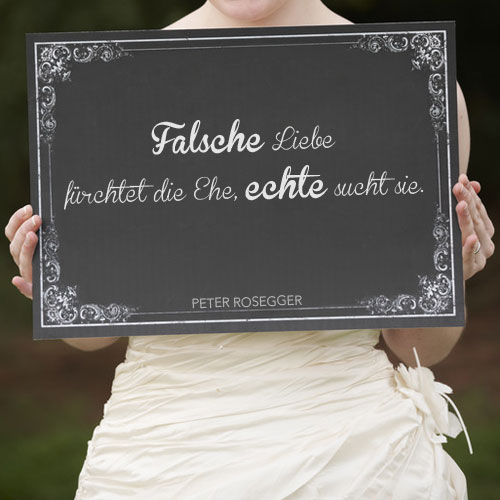 Mit einem Hochzeitszitat beschriebene Tafel in der Hand einer Braut