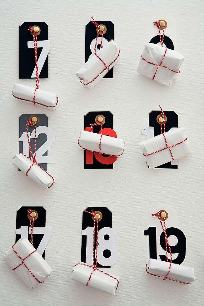 Bild von einem Adventskalender an der Wand mit großen Nummern und eingepackten Geschenken
