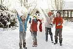 Vier Kinder spielen im Schnee, im Hintergrund steht ein Schneemann