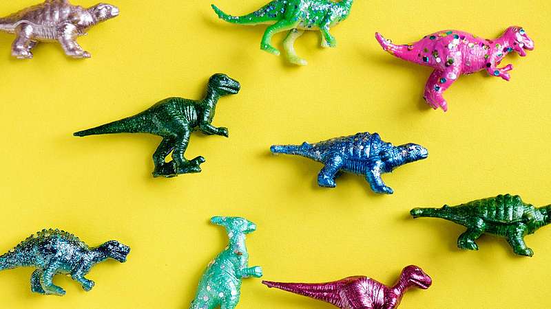 Bunte Dinosaurierfiguren auf gelbem Hintergrund