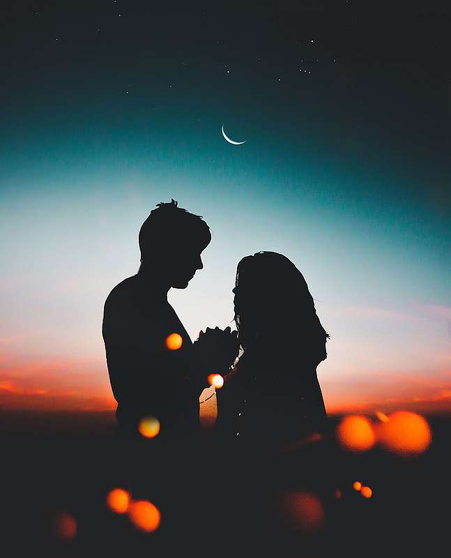 Silhouetten eines Paares vor einem Nachthimmel mit Mondsichel