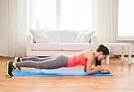 Frau macht Sport zu Hause / Planks auf Yoga-Matte