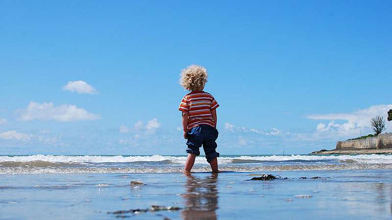 Kleines Kind mit blonden Locken am Strand