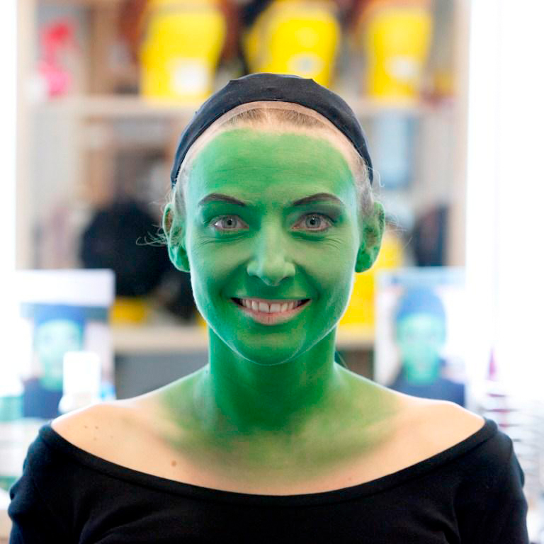Bild von einer Frau, die grün angemalt ist und schwarze Augenbrauen hat