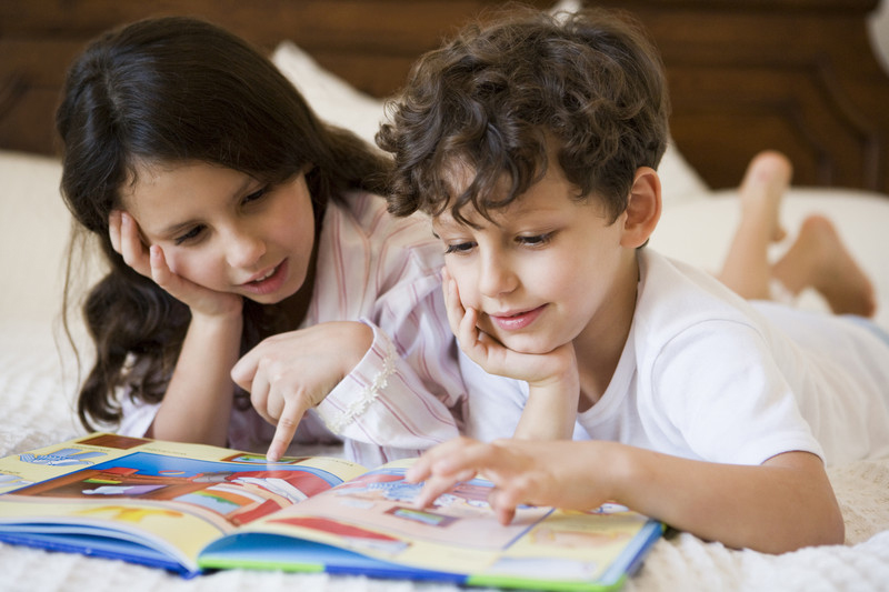 Kinder im Schlafanzug lesen gemeinsam ein Buch