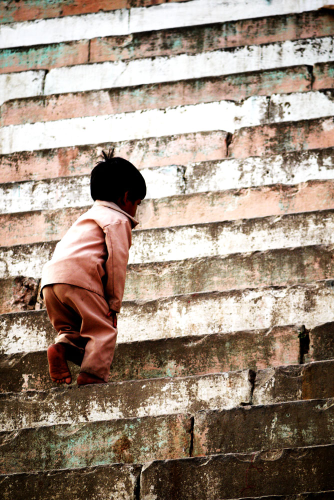 Kleines Kind läuft barfuß eine steile Steintreppe hinauf