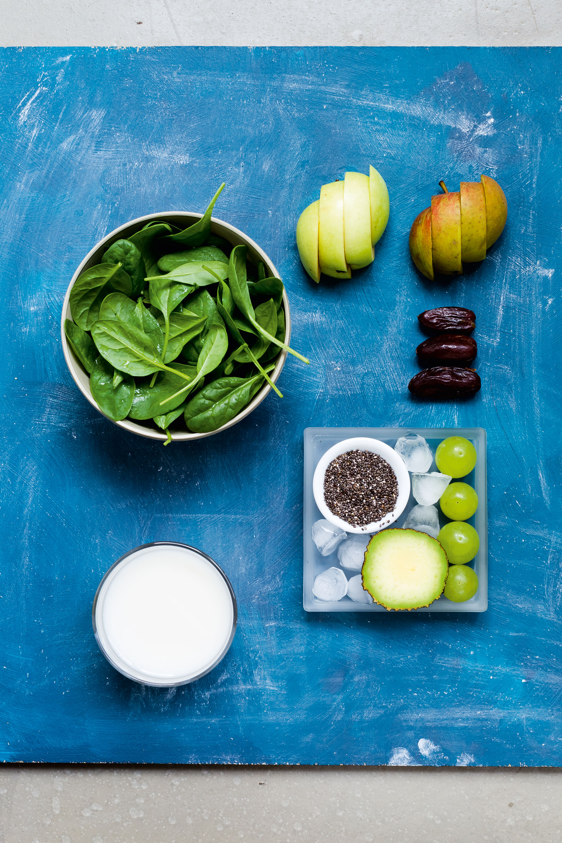 Zutaten für Smoothie mit Spinat, Apfel, Datteln, Chia-Samen, Trauben, Eiswürfeln und Pflanzenmilch