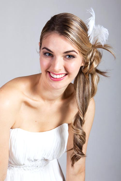 Brautfrisur, Frau mit blonden, langen Haare, seitlicher Zopf mit weißem Federaccessoire