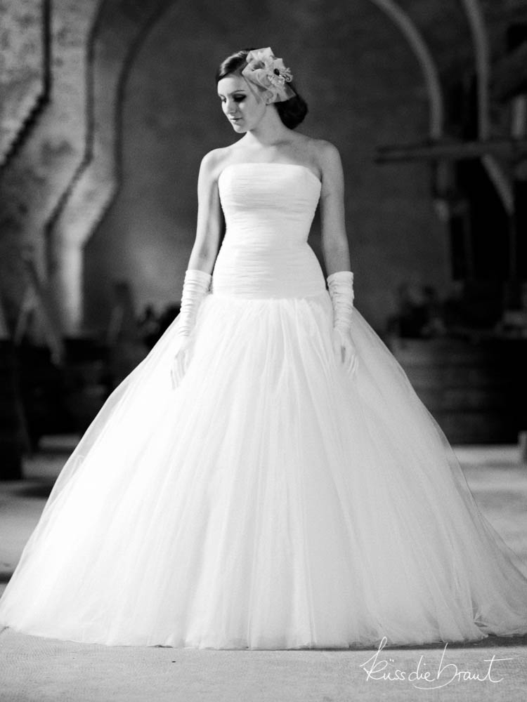 Schwarzweißbild von Model im schulterfreien Brautkleid von Lindegger. küss die braut
