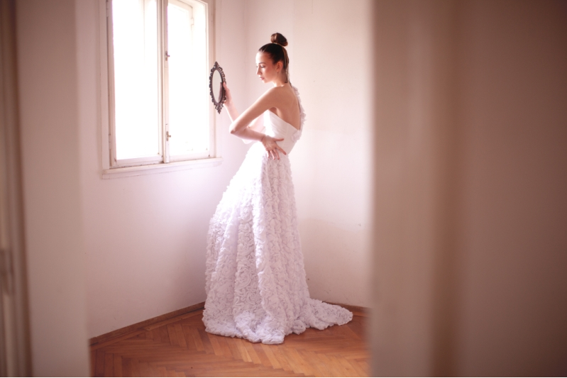 Model im Brautkleid von Magdalena Adriane blickt in einen Handspiegel