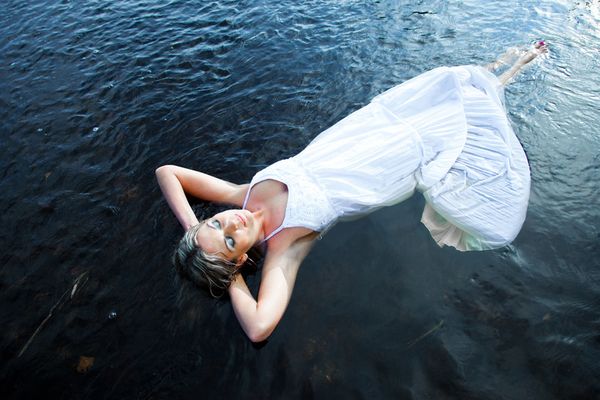 Symbolbild: Frau in weißem Kleid treibt entspannt auf dem Wasser