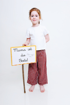 Mädchen hält Schild in der Hand, mit der Aufschrift: Mama ist die Beste!