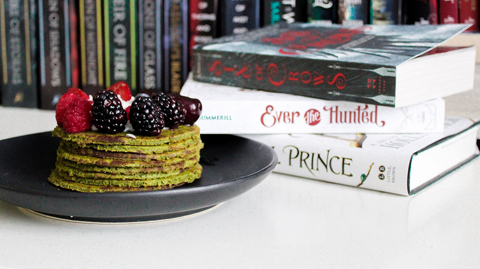 Tisch mit Büchern, daneben ein Teller mit Pancakes mit Beeren