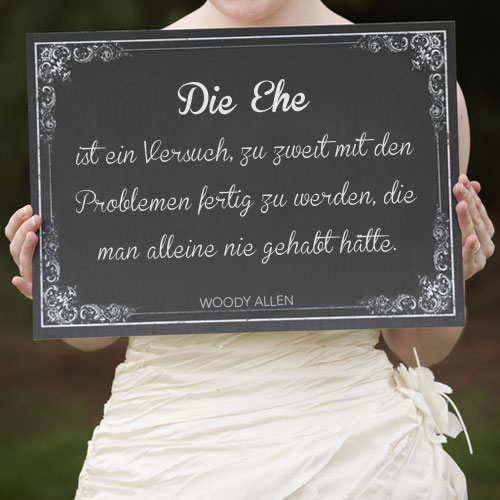 Mit einem Hochzeitszitat beschriebene Tafel in der Hand einer Braut