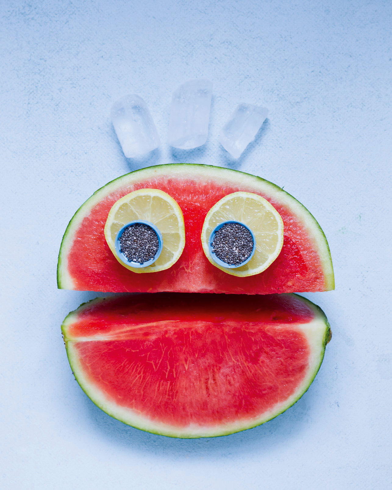 Melonengesicht: Halbe Wassermelone dekoriert mit Zitronenscheiben und Chiasamen als Augen