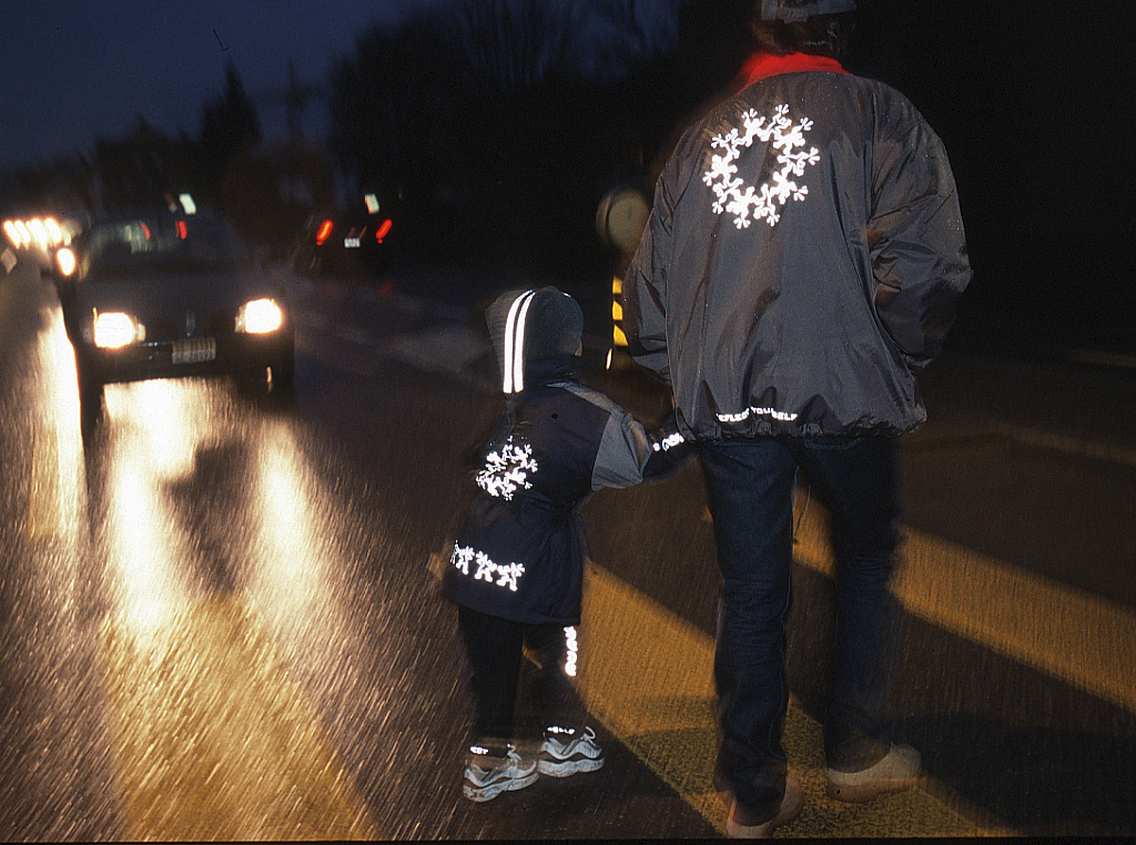 Mann mit Kind im Dunkeln auf dem Zebrastreifen - Kleidung mit Reflektoren