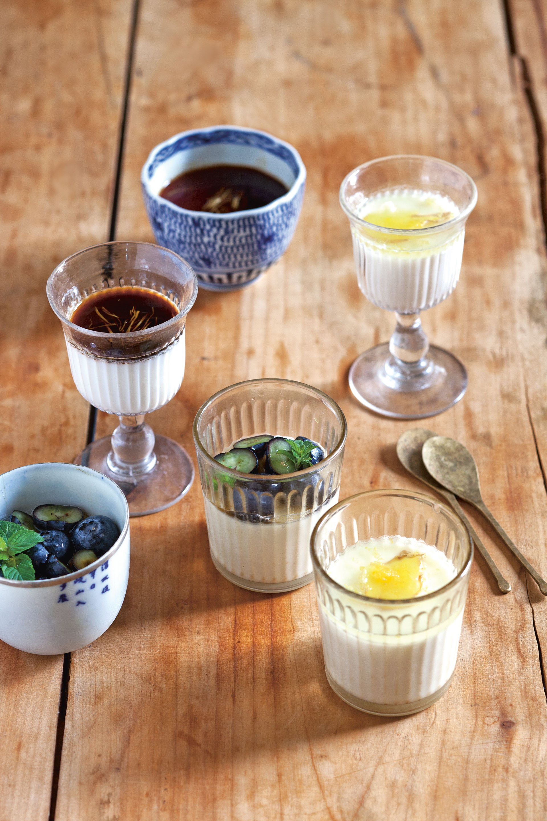 Japanischer Milchflan in Gläsern mit mit marinierten Heidelbeeren, Sauce aus schwarzem Zucker und Ingwer-Zitronen-Sauce