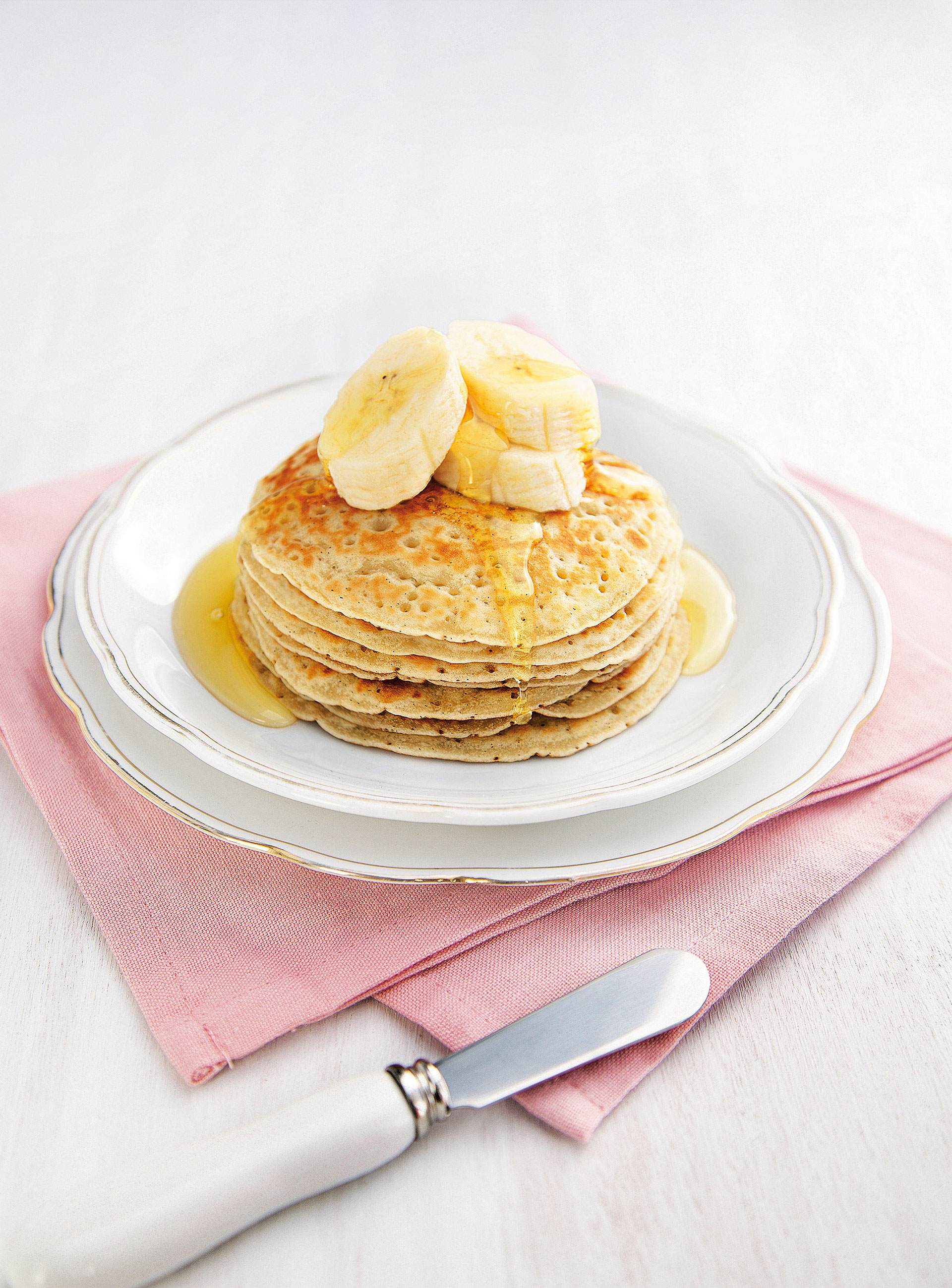 Gestapelte Pancakes mit Bananenscheiben und Ahornsirup